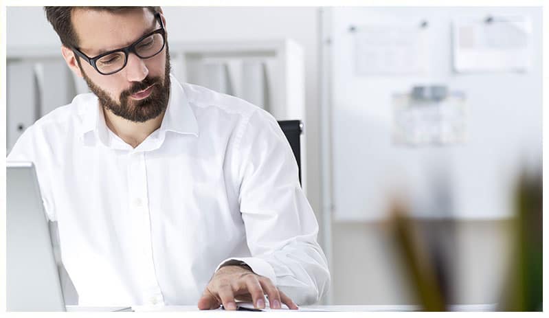 Adult man at his laptop looking over paperwork