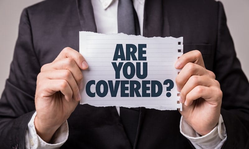 A businessman is holding up a piece of paper with the words: ARE YOU COVERED?