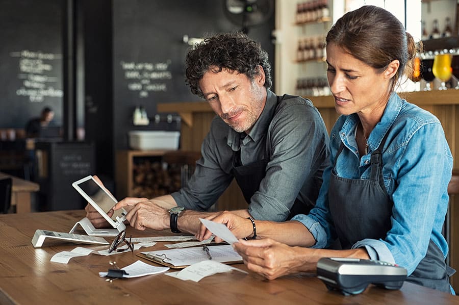 woman and man sitting in a cafe looking at financial documents