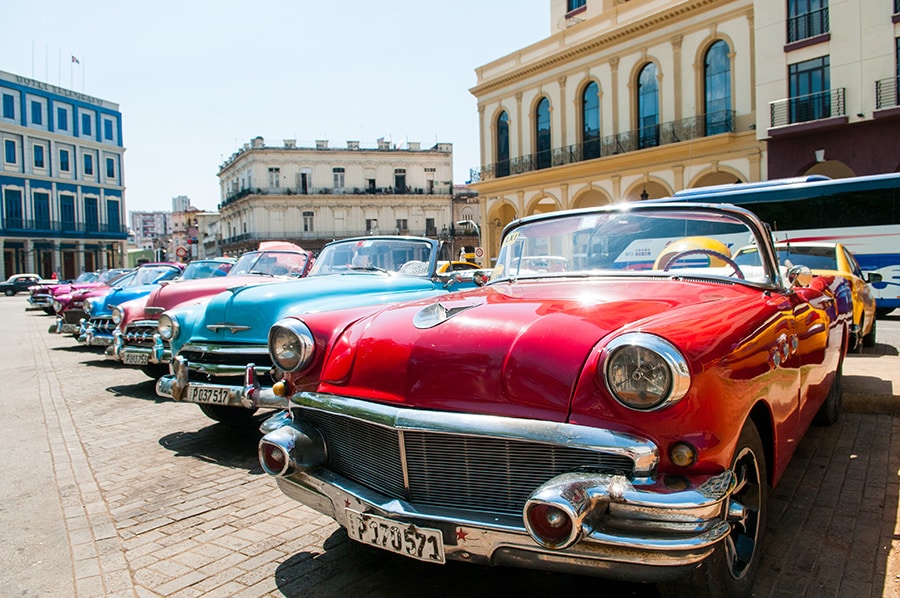 A line up of multiple classic cars in different makes, models, and colors.